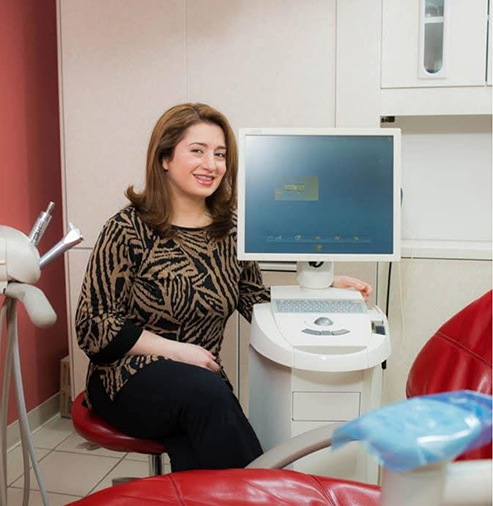 Doctor Mazhari smiling next to a chairside computer monitor