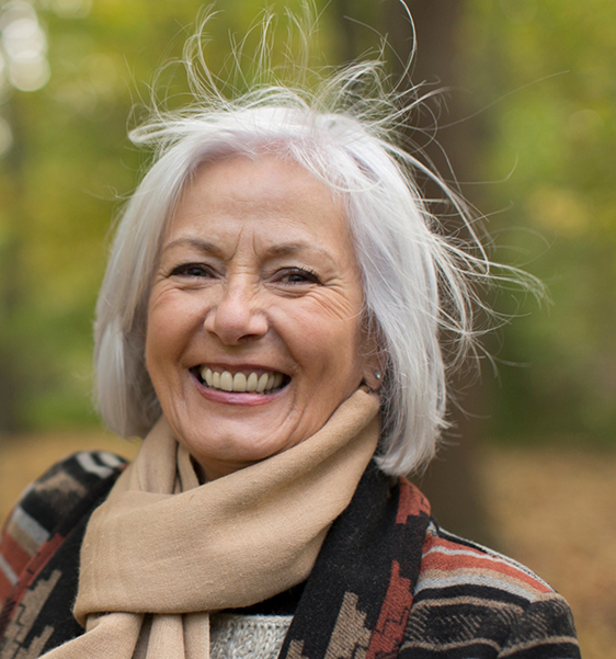 Senior woman smiling outdoors with All-on-4 dental implants in Alexandria