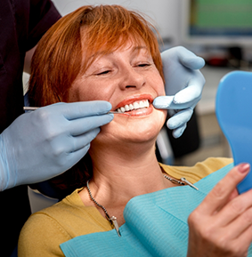 Woman in the dental chair admiring her smile in a mirror