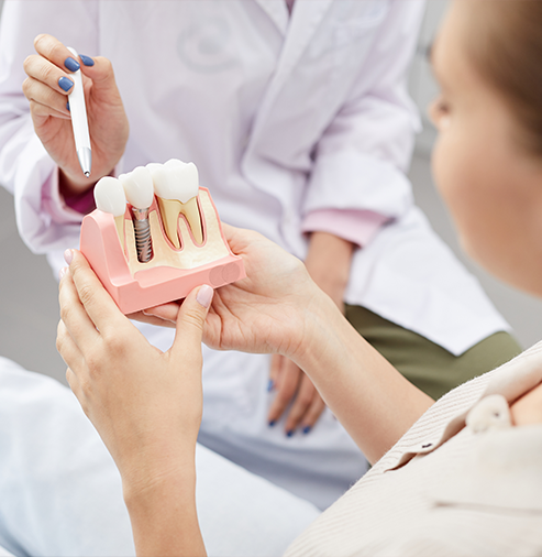 Dentist showing a model of a dental implant to a patient