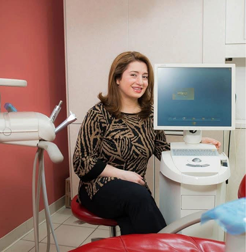Doctor Mazhari smiling next to a chairside computer monitor