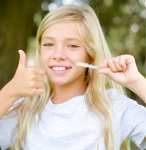 Teenage girl holding Invisalign and giving a thumbs up