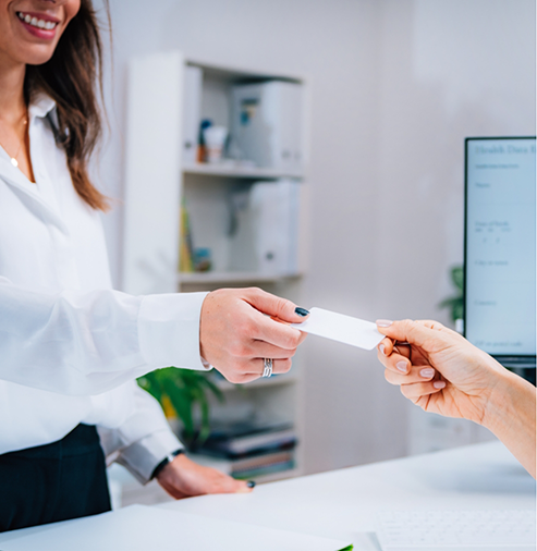 Dental patient handing a payment card to a team member