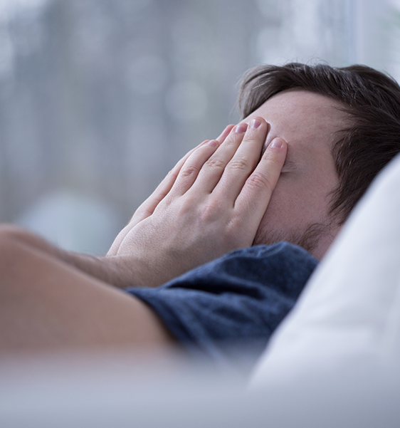 Man laying in bed rubbing his eyes