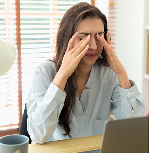 Tired woman rubbing her eyes at her desk