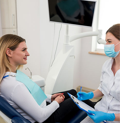Woman in the treatment chair talking with her dentist
