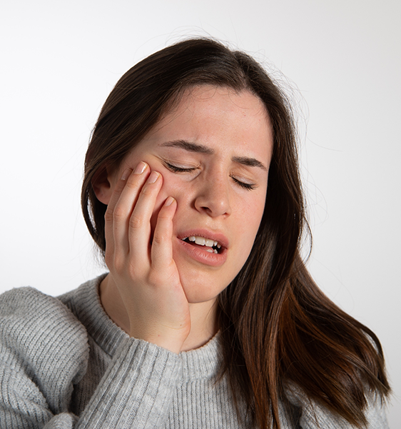 Woman holding her cheek in pain before tooth extraction in Alexandria